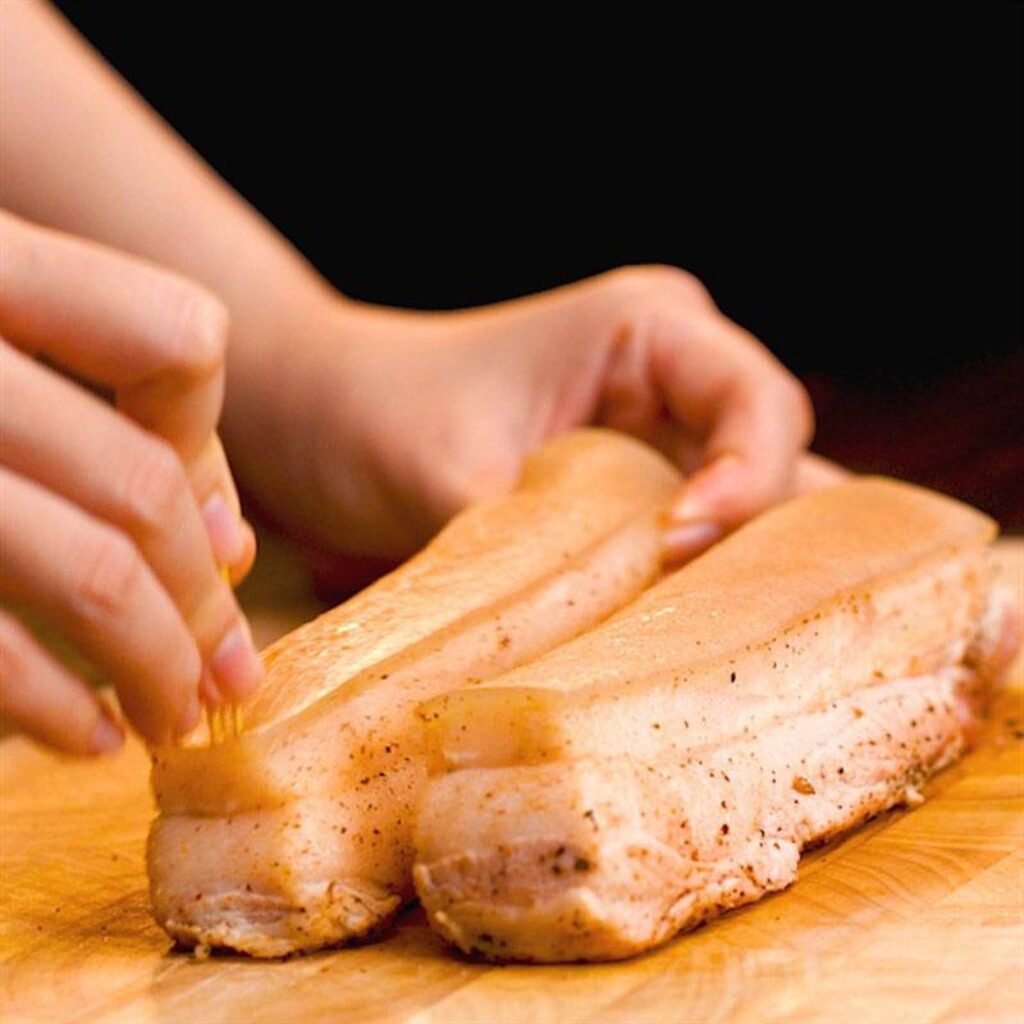 Xăm da và quét giấm lên bề mặt thịt ba chỉ trước khi nướng.